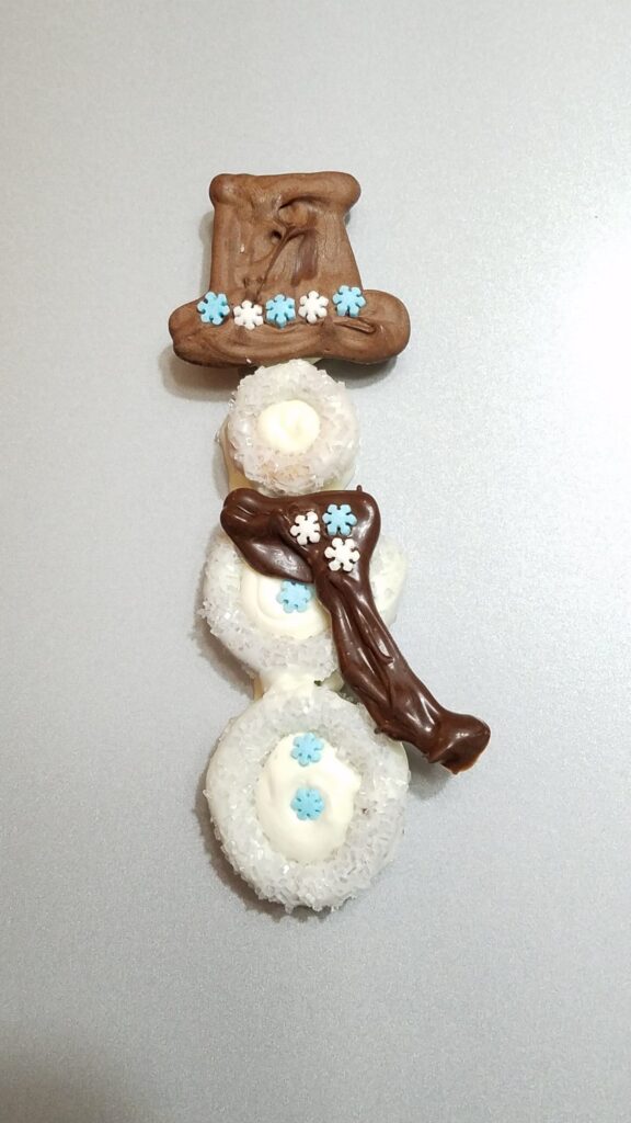 hat and scarf with snowflakes on chocolate covered snowman pretzel