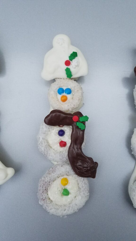 cute snowman pretzel covered in chocolate with hat and scarf