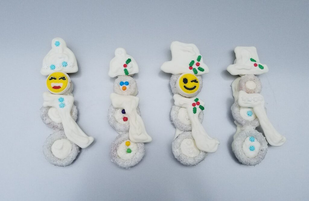 4 white chocolate covered snowmen with scarves and hats and faces