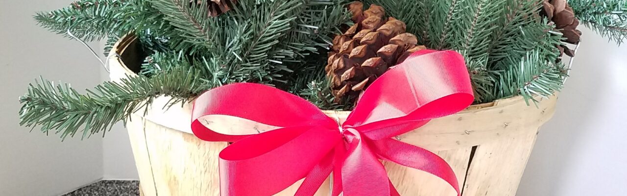 Evergreen Christmas basket with red ribbon and pine cones
