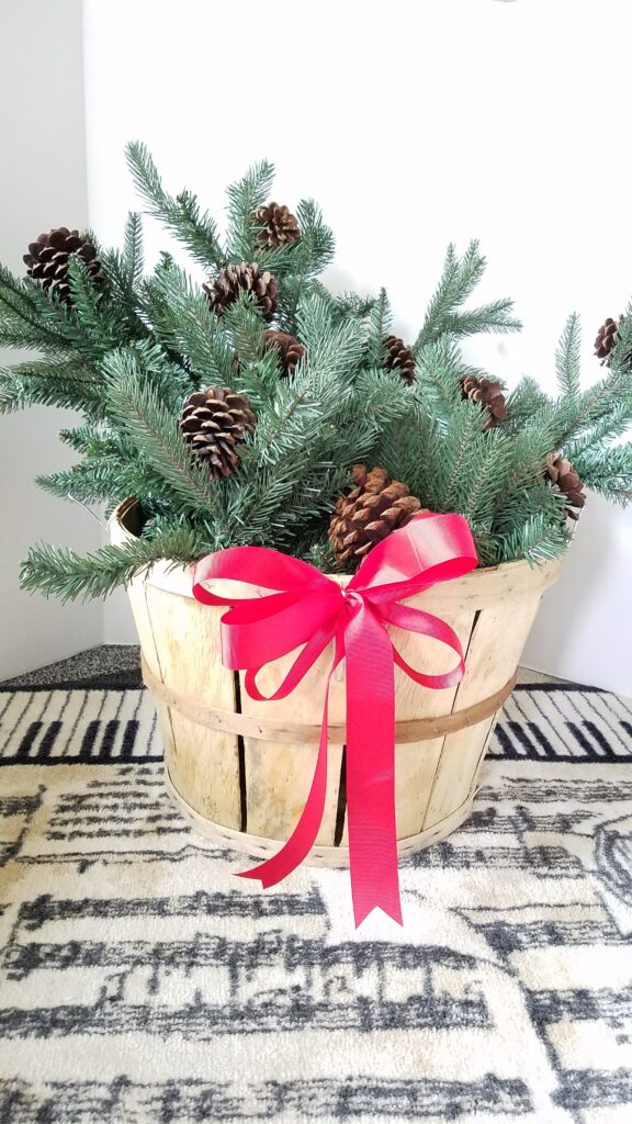 Evergreen Christmas basket with red ribbon and pine cones