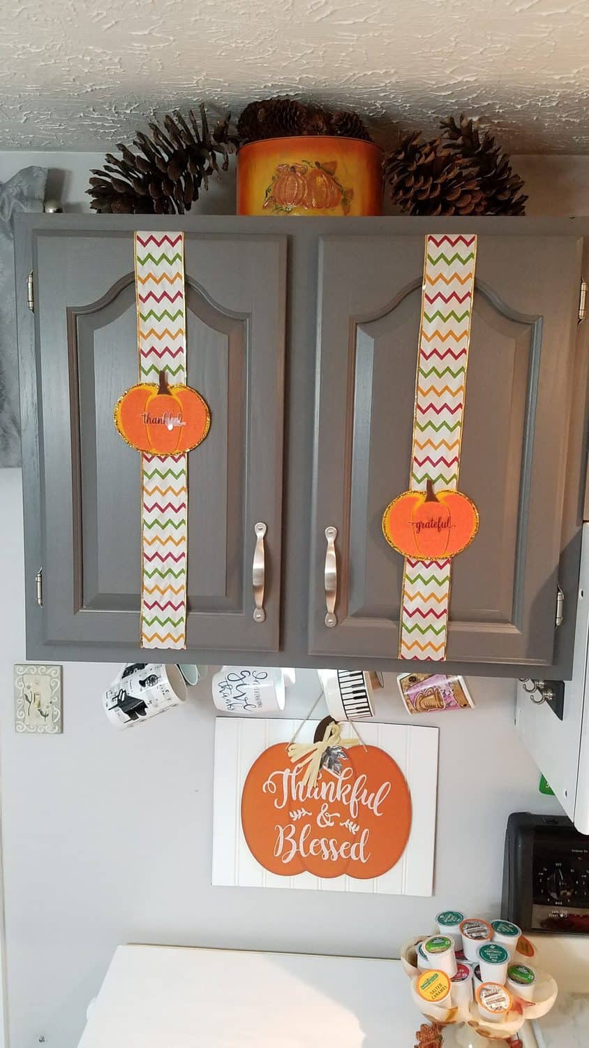 orange felt pumpkins on chevron ribbon on gray cabinet doors