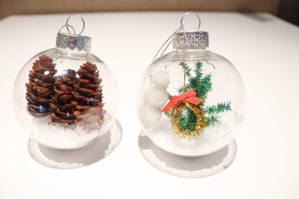 pinecones in a clear ornament, and a winter scene in another clear ornament