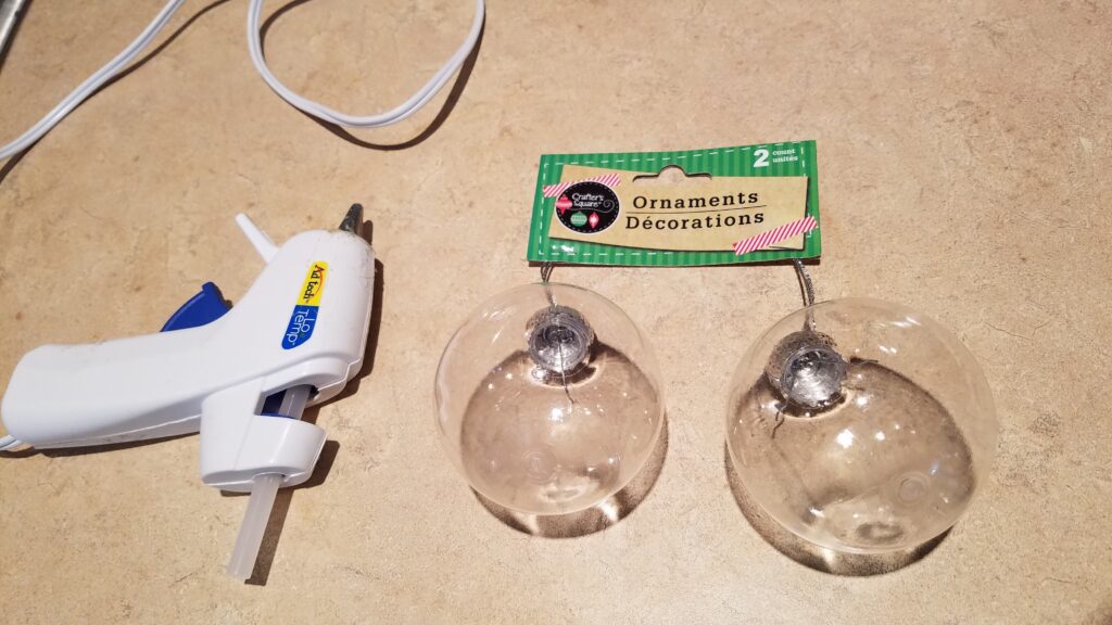two clear Christmas ornaments and a glue gun