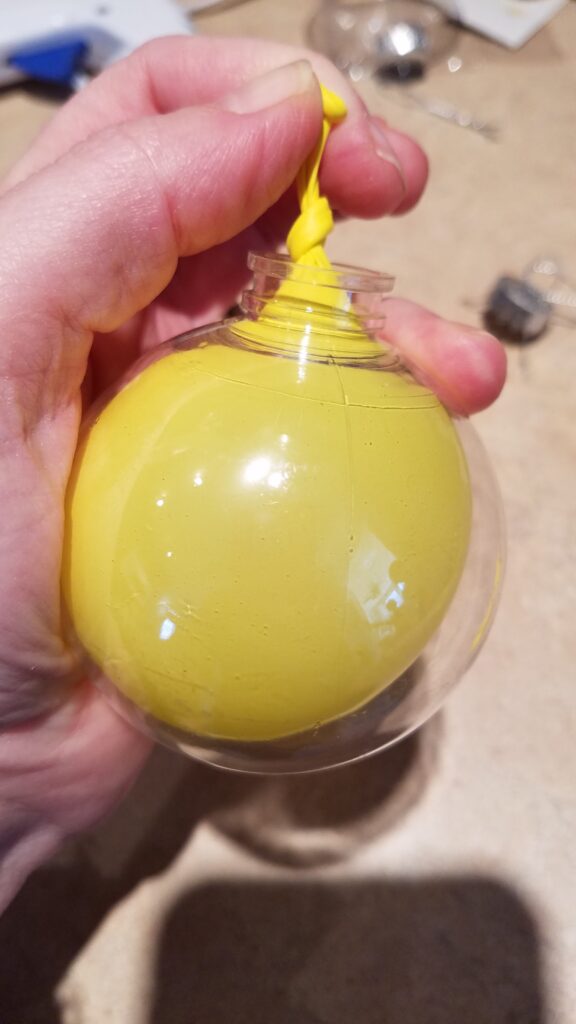 inflated yellow balloon in a clear Christmas ornament