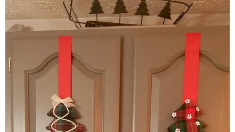 fabric Christmas trees on red ribbon on gray cabinet doors