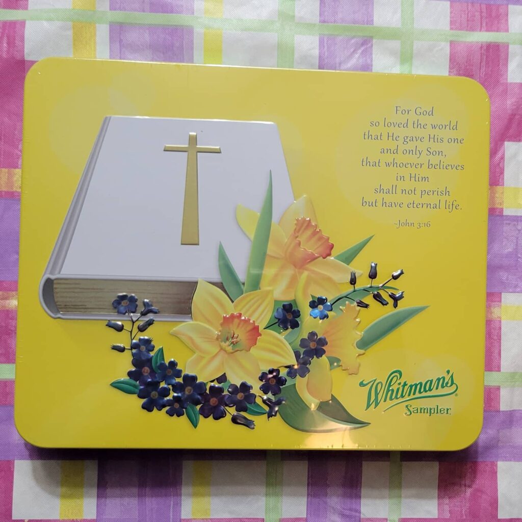 Yellow Whitman's chocolate tin with white Bible and John 3:16 on it