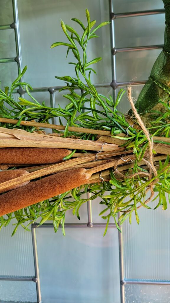 closeup of greening pins holding cattails to wreath