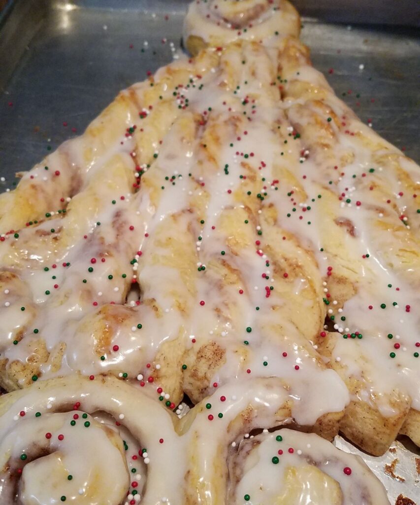 frosting on cinnamon rolls with red, green, and white nonpareils