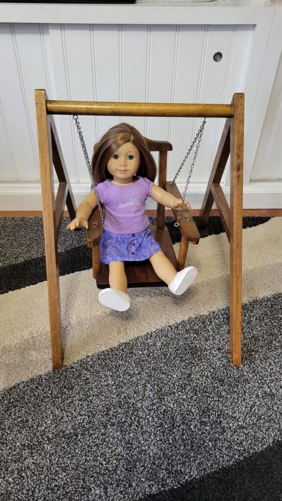 American girl doll in a wooden swing