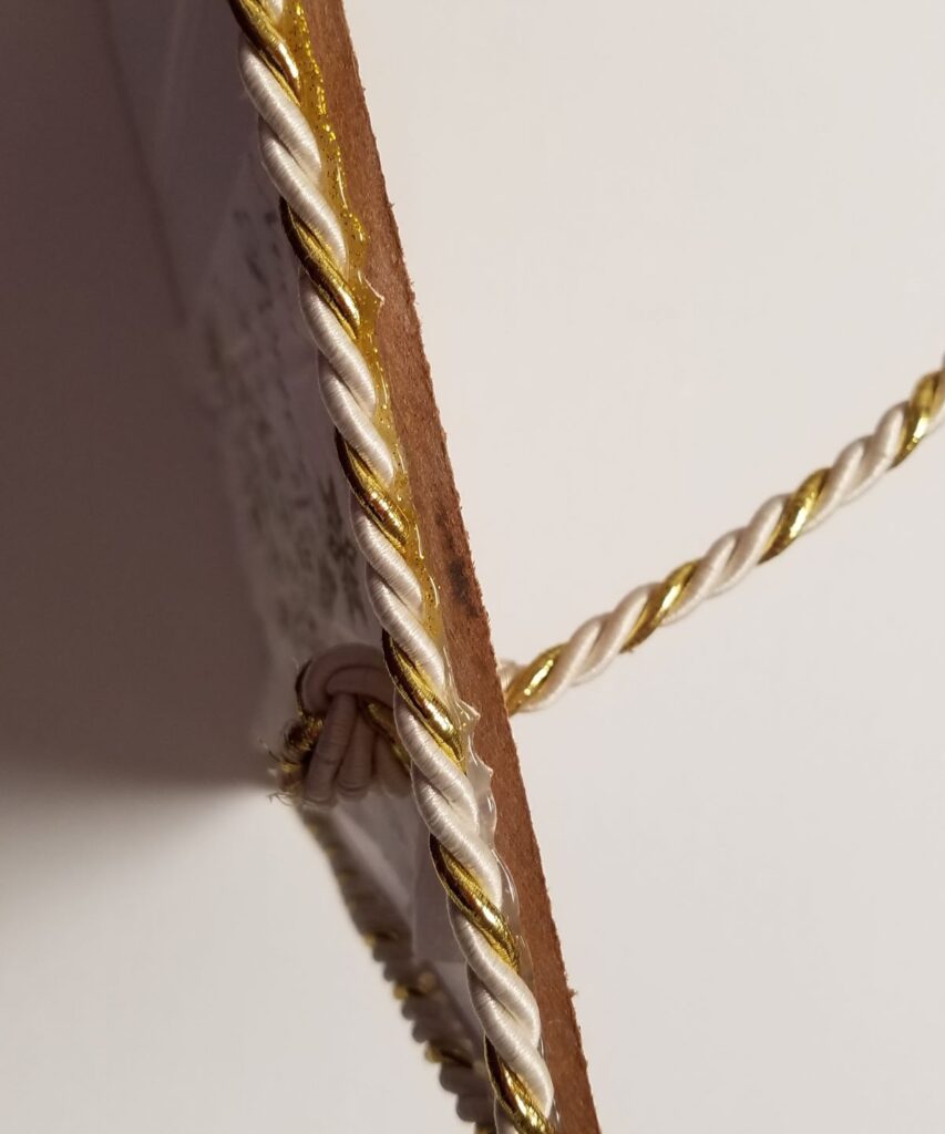 gold and white cord on edge of sign