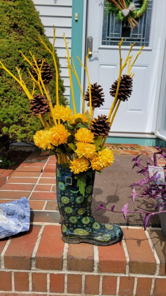 faux yellow flowers, pine cones, dried stems in a rain boot