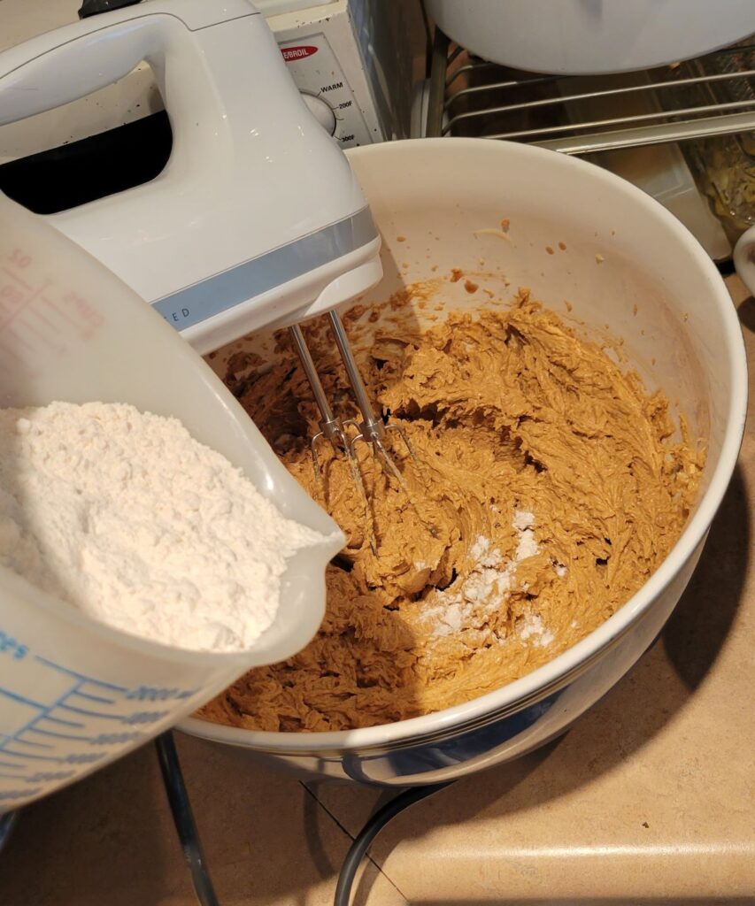 pouring dry ingredients into cookie dough