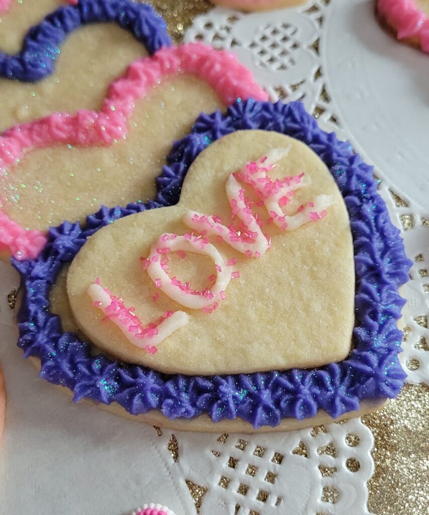 heart shaped cookie with the word LOVE and purple frosting