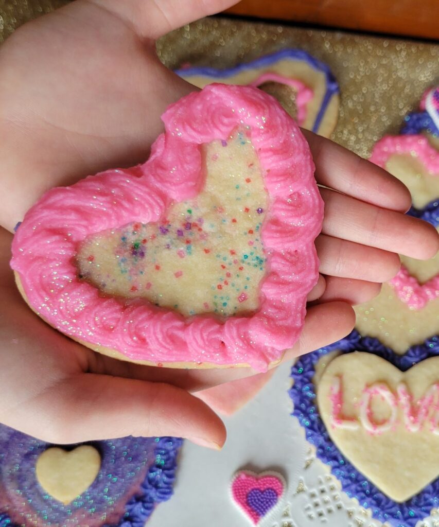 pink frosted heart cookie in hands