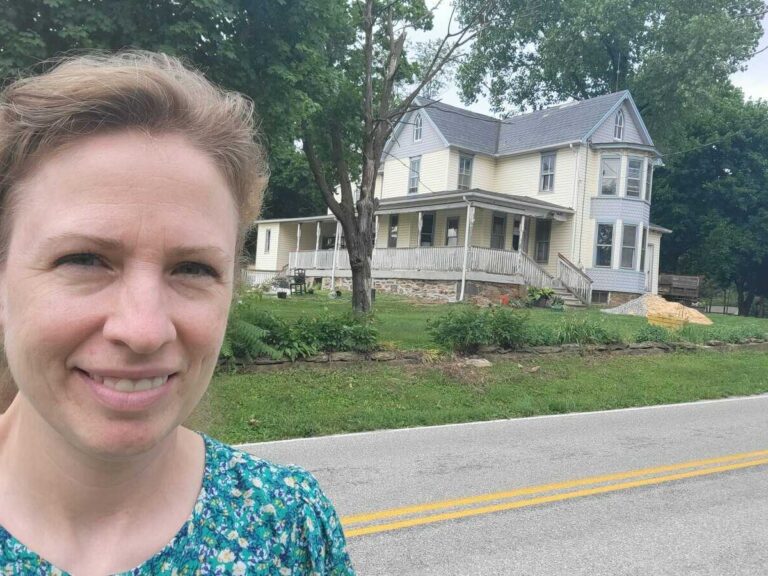person in front of large farmhouse