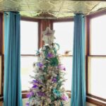 purple and teal Christmas tree in front of bay windows in dining room