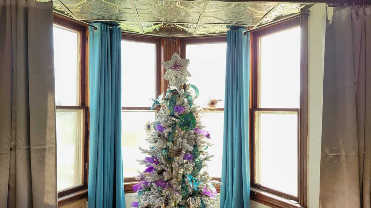 purple and teal Christmas tree in front of bay windows in dining room