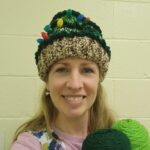 woman wearing Christmas hat holding green yarn