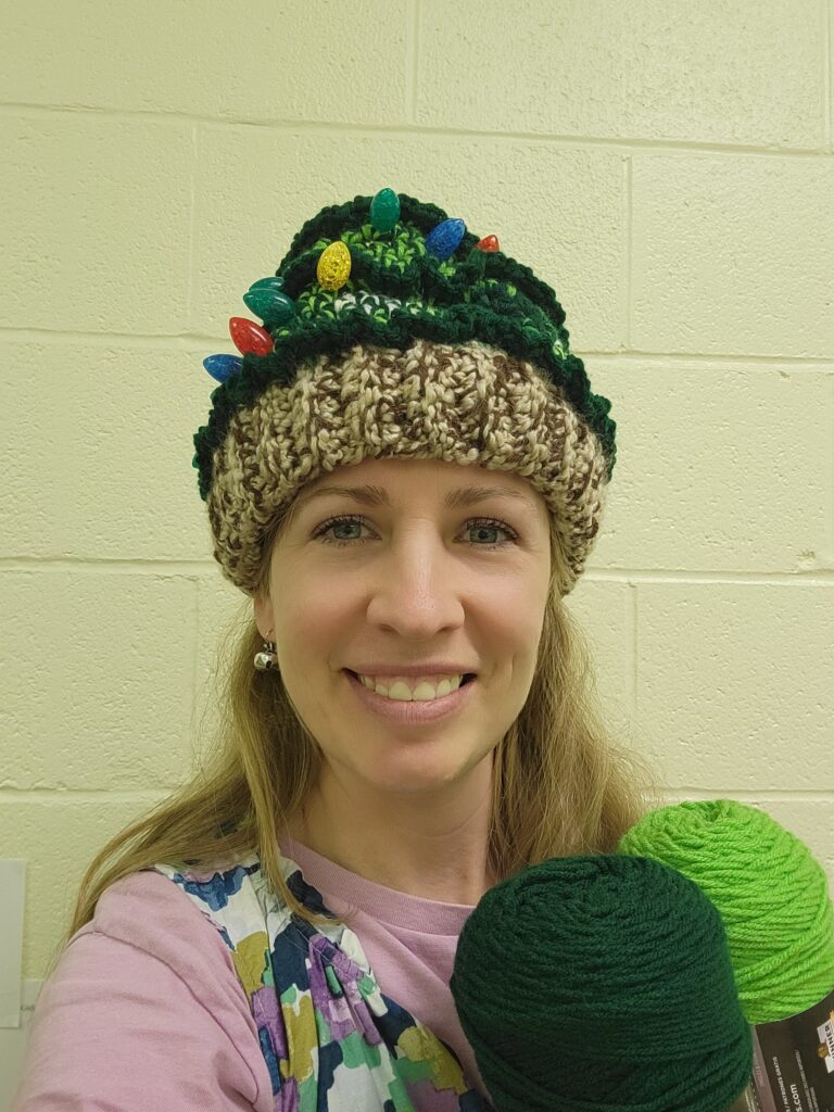 woman wearing Christmas hat holding green yarn