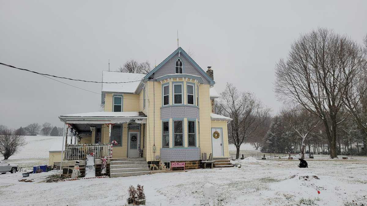 blue and yellow old farmhouse in the snow