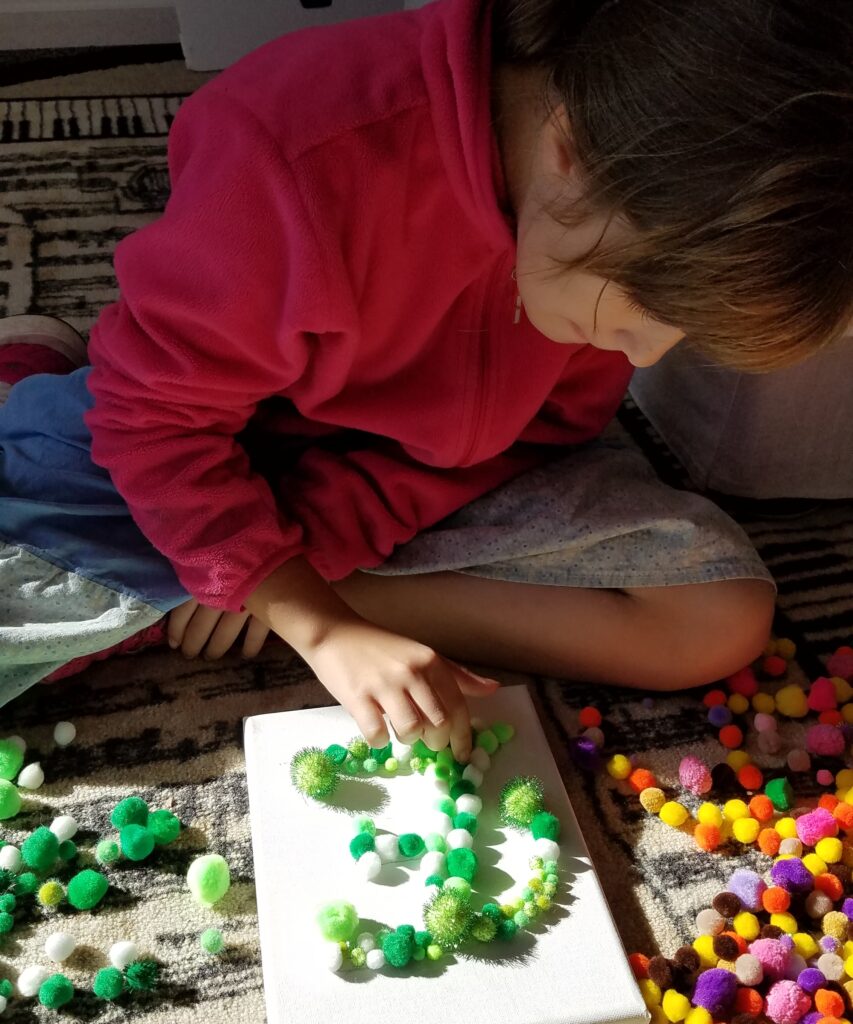 gluing the letter E in pom poms