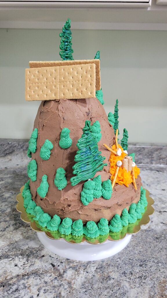 side of campfire cake with tent and trees